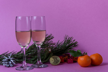 Two glasses of champagne and bitcoin on the table.の写真素材