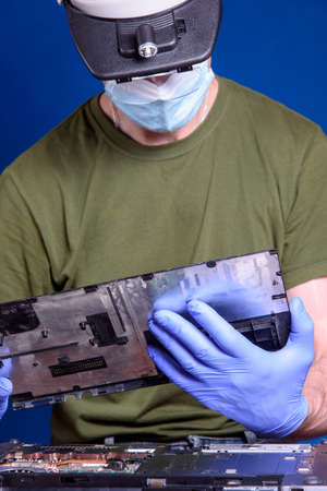 A man in a medical mask repairs a laptop. Computer repair.の写真素材