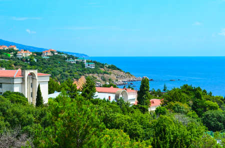 Sunny resort town and a view from the hotel window of lush greenery and houses near the sea coastの写真素材