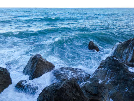 Salt sea waves rolling on large coastal rocks during an evening stormの写真素材