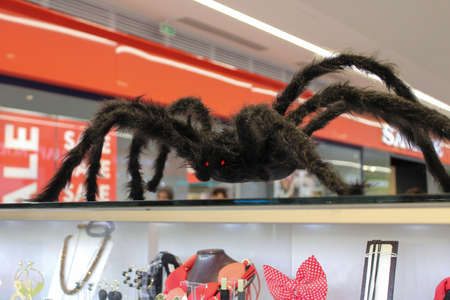 Fluffy frightening figure of a large red-eyed spider displayed on Halloween in a shopping center window as a decorationの写真素材