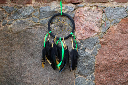Black contrasting dreamcatcher talisman with a net on the background of ancient masonry with beautiful textured cobblestone patterns close-upの写真素材