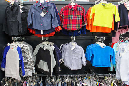 Different clothes for boys hanging in order on a hanger in a clothing row for sale in a shopping centerの写真素材