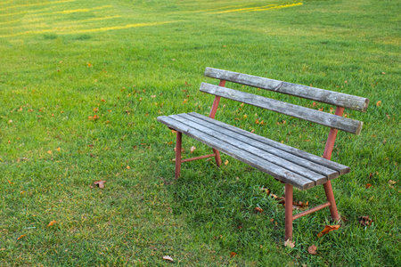 lonely old wooden bench with gray worn boards for relaxing on a walk on a lawn vast and emptyの写真素材