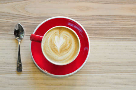 Top view of a red cup of hot coffee and a teaspoon on the wooden tableの写真素材
