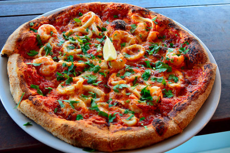 Pizza with shrimps, seafood and lemon.