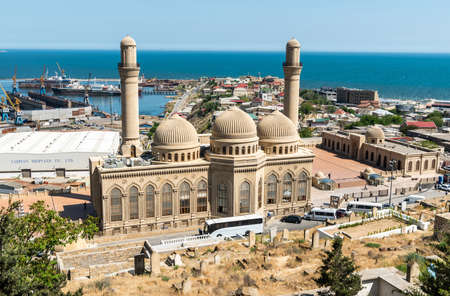 Bibi-Heybat, Baku, Azerbaijan - May 12, 2019. View over Bibi-Heybat mosque in Baku, with shipyard facilities, Caspian Sea and Bibi-Heybat settlement in the background. The existing structure, built in the 1990s, is a recreation of the mosque with the sameのeditorial素材
