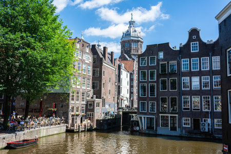 Amsterdam, The Netherlands â June 22, 2016. View of Oudezijds Voorburgwal canal and street in De Wallen in the centre of Amsterdam. View toward Basilica of Saint Nicholas, with boats and people.のeditorial素材