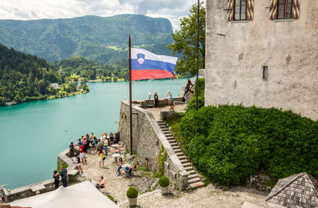 Bled, Slovenia â July 6, 2019. A terrace in the courtyard of Bled medieval castle in Slovenia, with Slovenian flag and tourists.のeditorial素材