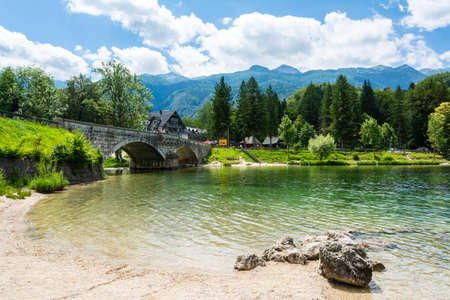 Ribcev Laz, Slovenia â July 7, 2016. View of Lake Bohinj in Slovenia, in summer. View with the bridge spanning Sava Bohinjka river, people and buildings.のeditorial素材