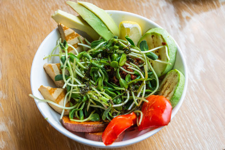 Vegan bowl with avocado, grilled tofu, zucchini and sweet potato, with greens and nuts on top, in Russia.の写真素材