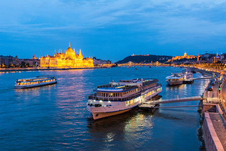 Budapest, Hungary â June 6, 2017. View of Danube river in Budapest, toward the Parliament building, with cruise boat in the foreground, at night.のeditorial素材