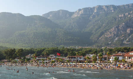 Akyaka, Mugla, Turkey - July 29, 2016. Akyaka beach in the centre of Akyaka village in Mugla province of Turkey, with Sakar mountains in the background, and people.のeditorial素材