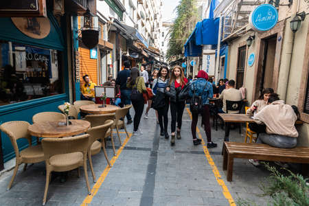 Izmir, Turkey - March 2, 2019. Narrow cafe-lined street in Alsancak district of Izmir, with commercial properties and people.のeditorial素材