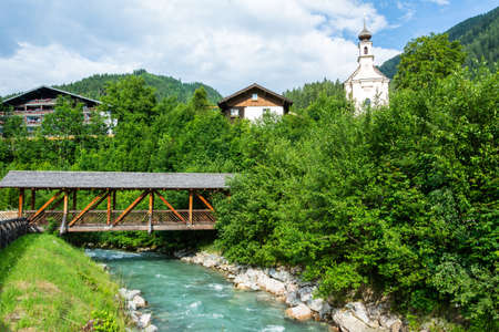 View over Enns river in Flachau, Austria, with a covered bridge and parish church in the background.のeditorial素材