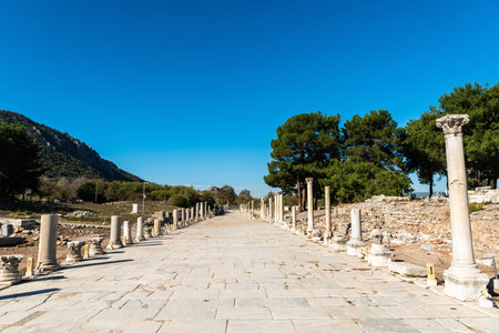Harbour Street in Ephesus, Turkey. Formally the Arcadian Way, Harbour Street was built by Byzantine emperor Arcadius in a late attempt to revive the fading city. At the time, it was Ephesusâ most lavish thoroughfare, illuminated at night by 50 streetlights on its colonnades, while water and sewage channels ran beneath its marble flagstones. View without people on a sunny day.の写真素材