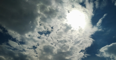 The sun Shining through puffy white clouds.の写真素材