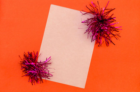 White sheet of paper decorated with tinsel on a red background. Invitation card, frame. A photo.