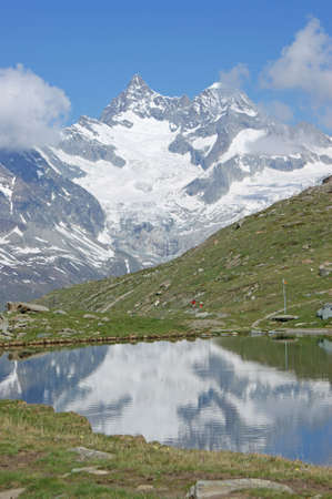 Summer in the Swiss alps and a lake where the mountains are reflecting in a lakeの写真素材