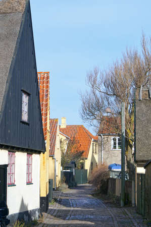 The old part of Dragoer which is a cozy, picturesque maze of alleys with yellow and white painted houses and cobblestone streets built in the traditional Danish style.の写真素材