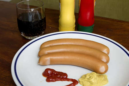 hot dogs with sauces and a drinkの写真素材
