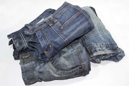 pile of several blue jeans over white backgroundの写真素材
