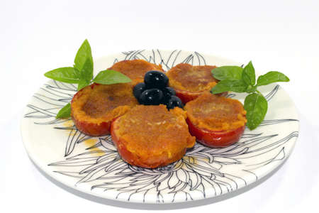 stuffed tomatoes on a decorative dish with basil and black olivesの写真素材