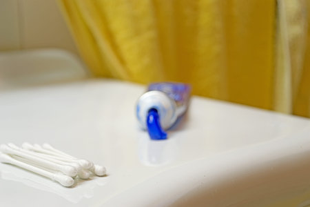 cotton swabs on a sink with a toothpaste tube in the background