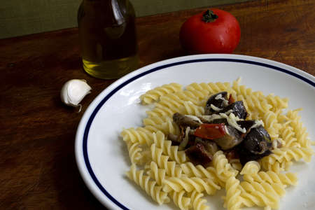 fusilli and eggplant on a wooden table with tomato, garlic and cruetの写真素材