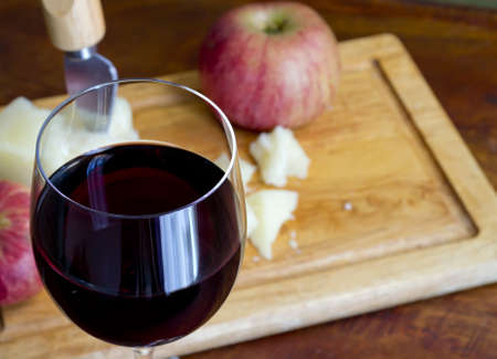 glass of red wine with cheese and apple in the backgroundの写真素材