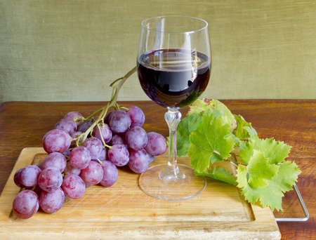 grape, wine and leaves on a cutting boardの写真素材