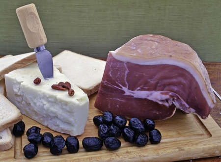 ham and cheese with olives on a cutting boardの写真素材