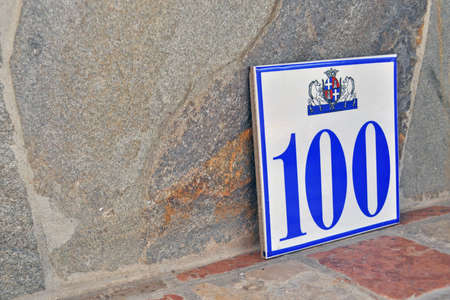 "one hunderd" residencial plate number on a stoned-counter topの写真素材