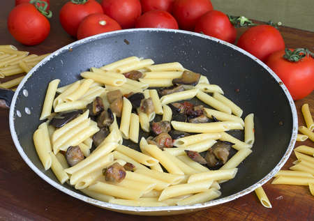 pan with pasta and eggplant on a wooden tableの写真素材