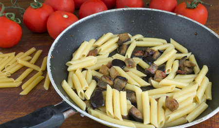 pan with pasta and eggplant on a wooden tableの写真素材