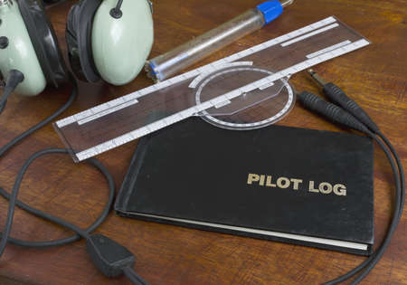 pilot log on a wooden table with headset, fuel tester and plotterの写真素材