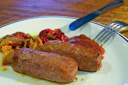 two sausages on a plate with peppers and red spicy sauceの写真素材