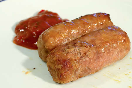 two sausages with rd spicy sauce on a plateの写真素材