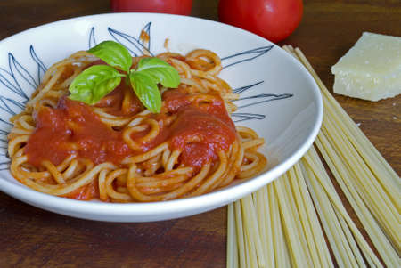 spaghetti with basil and sauce un a ceramic plateの写真素材