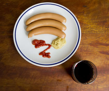 three hod dogs and a cold drink seen from aboveの写真素材