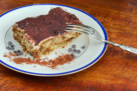 tiramisu dessert in a ceramic plate on a wooden table