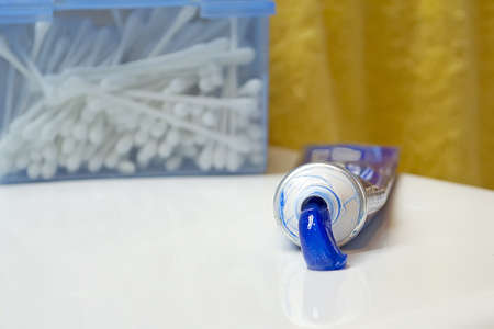 squeezed toothpaste tube and cotton swab box on a sinkの写真素材