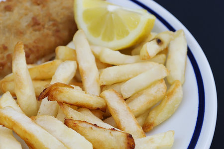 fish and chips with lemon on a white ceramic plate