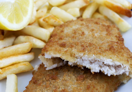 fish and chips with lemon on a white ceramic plate