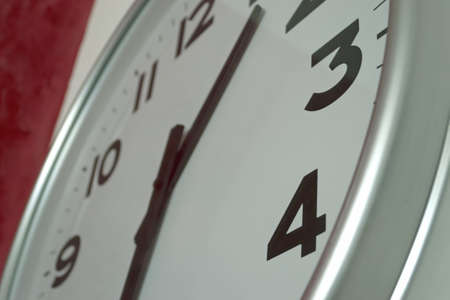 detail of a wall clock on a white and red wallの写真素材