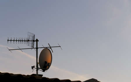 tv antenna and satellite dish at sunsetの写真素材