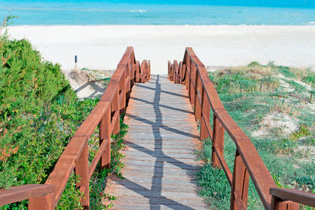 wooden boardwalk leading to La Pelosa white sandの写真素材