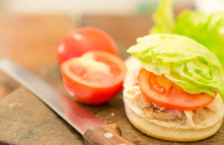 bun with knife, tomatoes and lettuce on a cutting board の写真素材