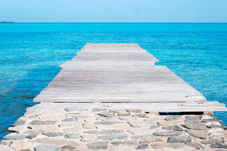 wooden pier over turquoise water in Sardiniaの写真素材
