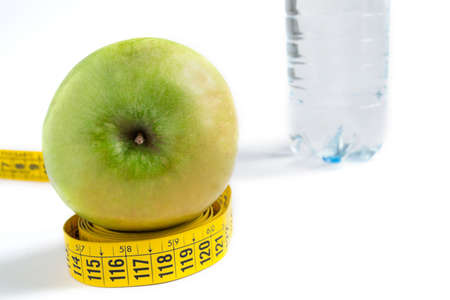 green apple on a yellow tape with a bottle of water in the backgroundの写真素材